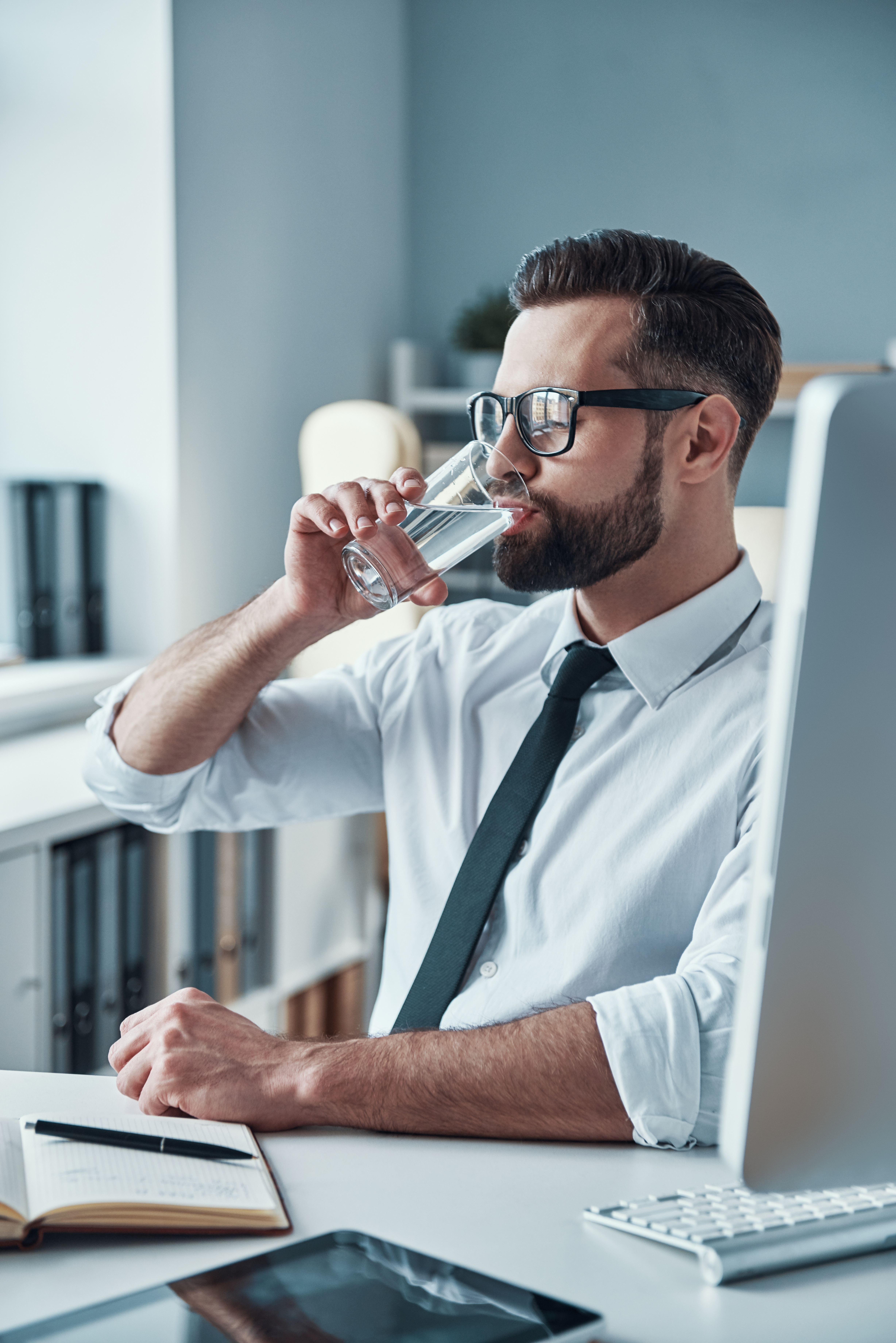 Hydration at the office boosts focus  Young businessman focused at his desk with a water bottle nearby, emphasizing hydration’s role in productivity