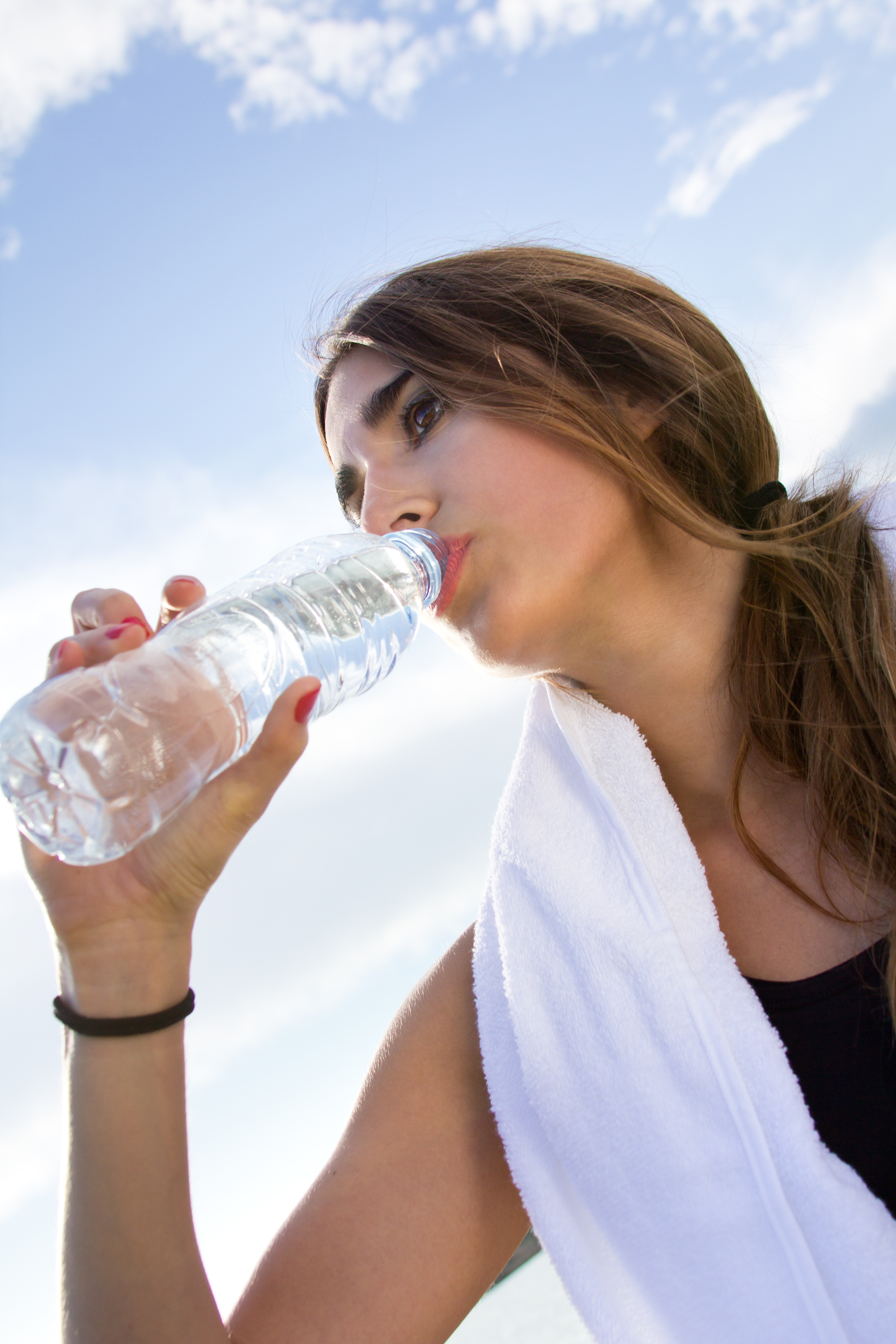 Stay hydrated before, during, and after activity Young woman drinking water after exercising outdoors, promoting hydration for energy and recovery